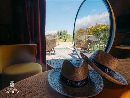 Straw hats inside a wine barrel suite with a view toward the vineyard terrace
