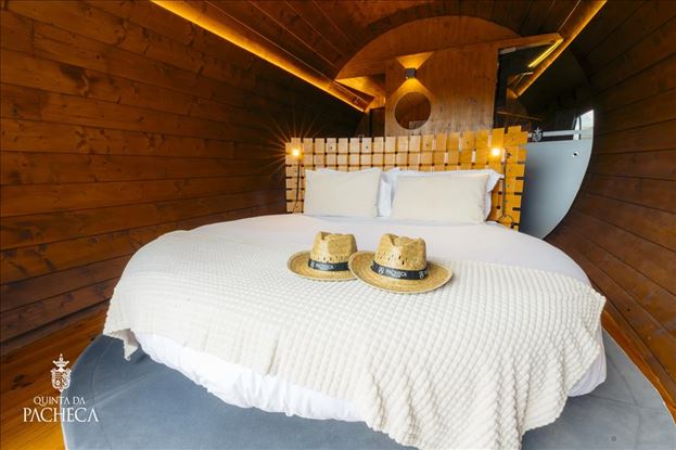 Warm wooden interior and comfortable bed inside a Quinta da Pacheca wine barrel suite